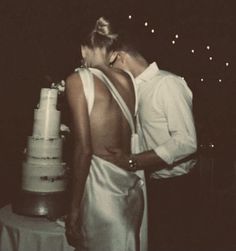 a man and woman standing next to each other in front of a cake