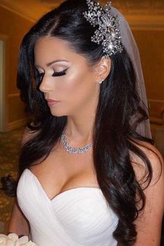 a woman in a wedding dress holding a bouquet and wearing a tiara with pearls on it