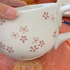 a person is holding a white cup with pink flowers on it