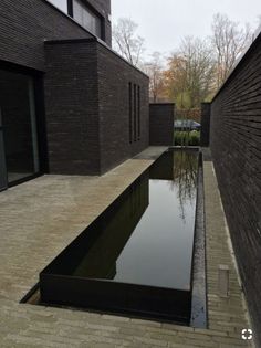 an empty pool in the middle of a brick walkway next to a building with large windows