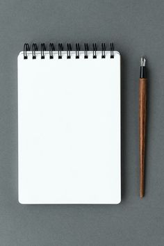 a notepad with a pen on top of it next to an empty notebook and pencil