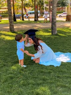 a woman kneeling down next to a little boy on top of a lush green field