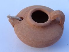 a clay vase with a white handle on the top and a stick sticking out of it