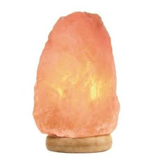 a himalayan salt lamp on a wooden base with a white background the light is orange