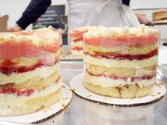 two cakes sitting on top of each other in front of a person standing behind them