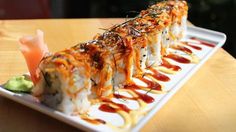 a sushi dish with sauce and garnish on a white plate sitting on a wooden table