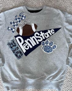 a gray sweatshirt with an image of a football and paw prints on the front that says penn state