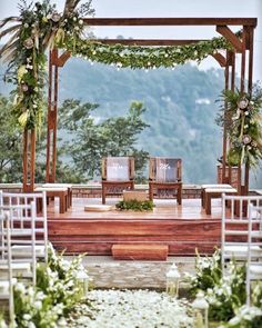 an outdoor wedding setup with chairs and greenery