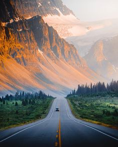 a car driving down an empty road in the mountains