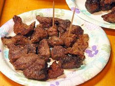 two plates with skewers of meat on them