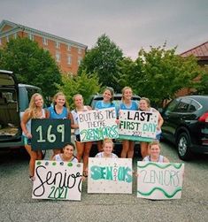 a group of young women holding signs in front of parked cars