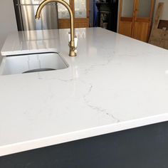 a white counter top with a gold faucet in the middle and a sink below it