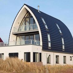 an unusual house with a curved roof and glass balconies on the second floor