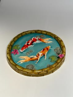 there is a bowl with two koi fish in it and flowers on the bottom