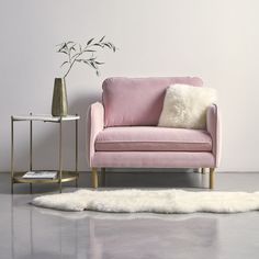 a living room with a pink couch and white rug on the floor next to a gold side table