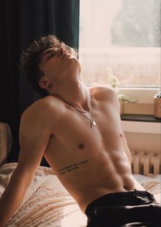 a shirtless man laying on top of a bed