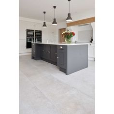 a large kitchen with an island in the middle and two pendant lights hanging from the ceiling