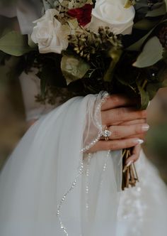 a woman holding a bouquet of flowers in her left hand and wearing a wedding ring