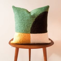 a green and black pillow sitting on top of a wooden table