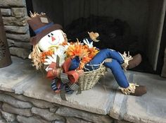 a stuffed snowman sitting on top of a fire place next to a basket filled with flowers