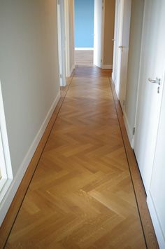 an empty hallway with hard wood floors and white walls