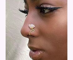 a close up of a woman wearing a nose ring with a flower on it's side