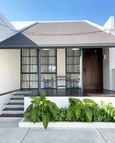 a house with plants in front of it and stairs leading up to the porch area