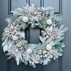 a wreath is hanging on the front door with pine cones and snowflakes