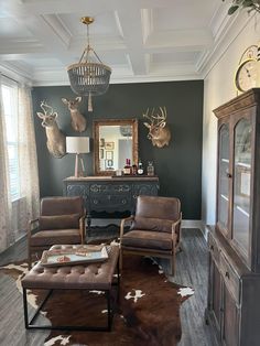 a living room filled with furniture and deer head mounted on the wall above it's windows