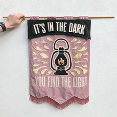 a banner hanging on the side of a building that says, it's in the dark you find the light