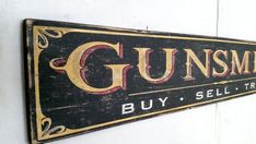 a sign on the wall that says gunsmike buy sell trade with gold lettering