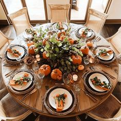 the table is set with pumpkins and greenery