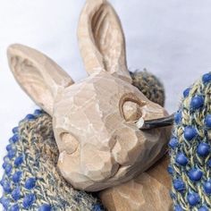 a wooden sculpture of a rabbit with blue beads around it's neck and head