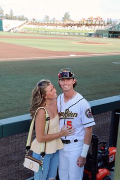 a man and woman standing next to each other on a baseball field