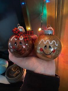 two christmas ornaments in the palm of someone's hand