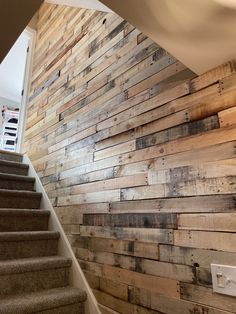 a stair case made out of wooden planks next to a wall with a light switch on it