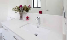 a white bathroom with flowers in a vase on the counter