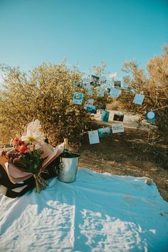 a table with flowers and other items on it in the middle of an open field