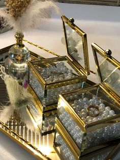 an assortment of jewelry sitting on top of a gold tray next to a white feather