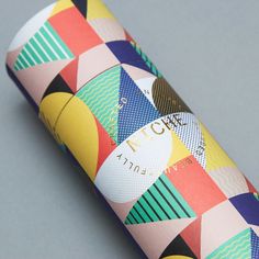 a colorful tube is sitting on a gray surface and it's made out of paper