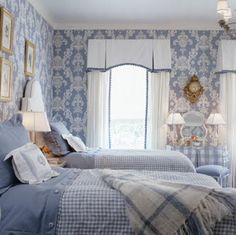 two beds in a room with blue and white wallpaper