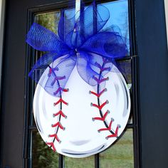 a baseball ornament hanging on a door with a blue bow around it's neck