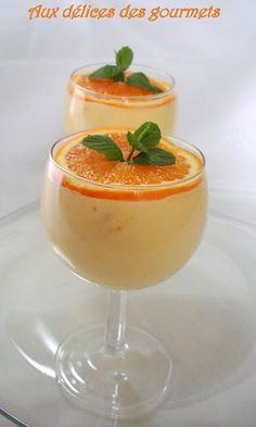 two glasses filled with orange juice and garnished with mint on a clear plate