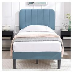 a bed with a blue headboard sitting on top of a white carpeted floor