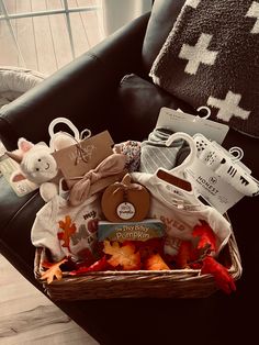 a basket filled with baby items sitting on top of a black leather chair next to a pillow