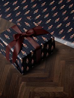 a gift wrapped in black wrapping paper with a red bow on it's side