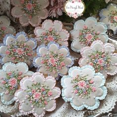 several decorated cookies are on a doily with pink and blue flowers in the center