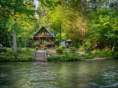 a house sitting on top of a river surrounded by trees