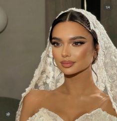 a woman wearing a veil and makeup looks at the camera while she is getting ready to walk down the aisle