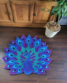 a blue and purple rug on the floor next to a potted plant